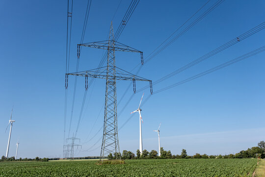 Electricity pylon with power lines and wind energy plants seen in Germany