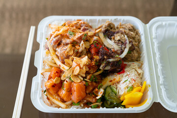 Overhead view of a Hawaiian poke lunch plate featuring spicy ahi, salmon, kalua pork, crab salad, and pickled vegetables. Clean presentation ideal for delivery or lifestyle food features.