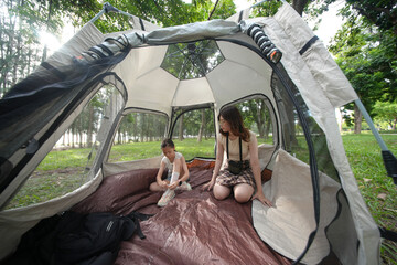 Mother and son enjoy a relaxing moment inside a spacious camping tent in a park