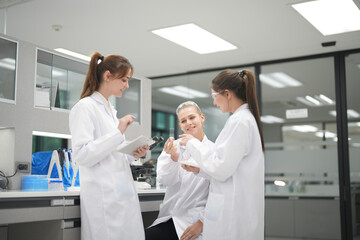 Three young scientists collaborate in a modern laboratory while analyzing samples and data