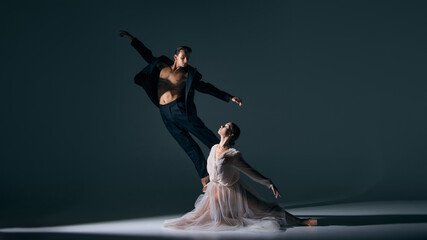 Male dancer leaping above female ballerina on stage with dramatic expression. Concept of passion, stage performance, emotional intensity, contemporary art, and creative movement.