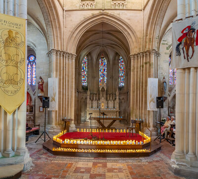 Langrune-Sur-Mer, France - 08 07 2025: Panoramic view of the altar with candles around, hangings, stone statues and stained glass windows inside the Saint-Martin Church