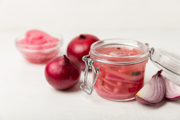Pickled onions in a glass jar on the table. pickled red onion. Vegetarian spicy dish. Delicious homemade marinated pickled purple onions . Space for text. Copy space.