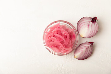 Pickled onions in a glass jar on the table. pickled red onion. Vegetarian spicy dish. Delicious homemade marinated pickled purple onions . Space for text. Copy space.