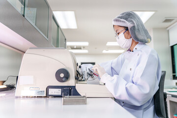 Technician operating lab equipment in a clean room setting during daytime