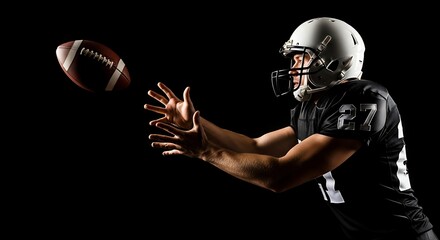 Football player catching a pass against black background