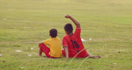 Two boys sitting on the edge of the field
