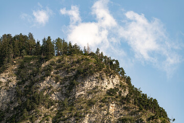 Rugged mountain peak with sparse trees under a blue sky in the early afternoon