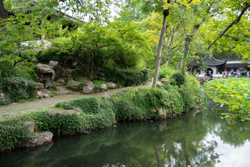 Decorative path in oriental style in green area near pond in Humble Administrator's Garden, classical Chinese garden in Suzhou, Jiangsu, Gusu District, China