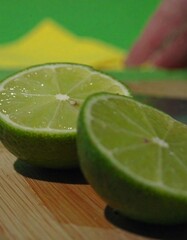 Two lime halves on a wooden board, blurred background