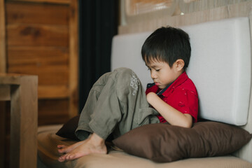 Cute little boy watching videos,relaxing at home.little boy lying down looking at the phone, close-up. little boy use of smart phone and lying down on sofa