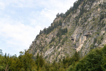 Naklejka premium Majestic mountain landscape with rocky cliffs and lush greenery under a bright sky