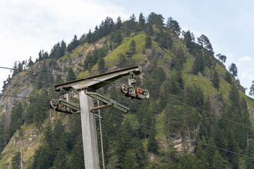 Mountain cable car infrastructure against a backdrop of lush green trees in a scenic landscape