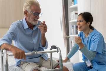 Fototapeta premium Asian female caregiver taking care of male elderly pensioner in homecare