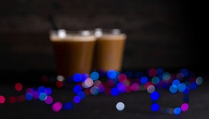 Two out-of-focus coffee drinks, colorful lights
