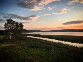 Sunset over the calm Halikonlahti bay with trees and grassy foreground near Salo, Finland, July 2018
