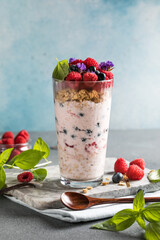 Granola with yogurt and fresh raspberries in glass on light background