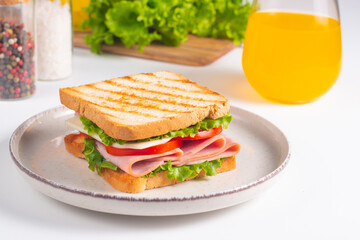 Close-up of two sandwiches with bacon, salami, prosciutto and fresh vegetables on rustic wooden cutting board. Club sandwich concept