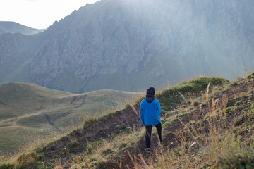 Fototapeta premium 9 year old boy climbs a mountain surrounded by mountains
