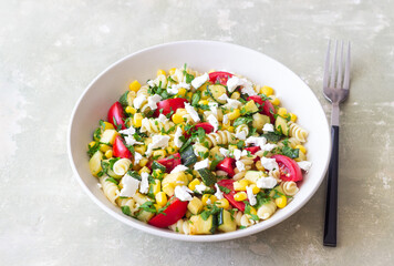 Pasta salad with tomatoes, zucchini, corn and feta cheese. Healthy eating. Vegetarian food.
