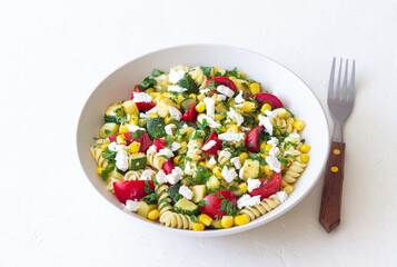 Pasta salad with tomatoes, zucchini, corn and feta cheese. Healthy eating. Vegetarian food.