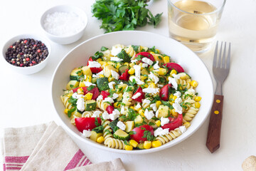 Pasta salad with tomatoes, zucchini, corn and feta cheese. Healthy eating. Vegetarian food.