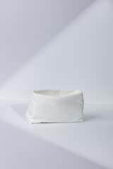 White fabric toiletry bag on minimalist background.