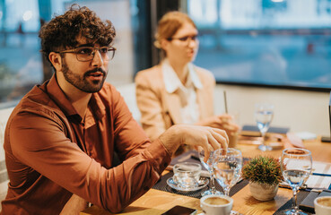Business people are actively engaged in a collaborative meeting at a modern office. They discuss strategies and share ideas over coffee, fostering teamwork and innovation in a relaxed atmosphere.