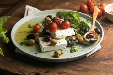 Bryndza cheese with grilled tomatoes and olives on rustic background
