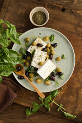 Salad with feta cheese, olives and basil on wooden background