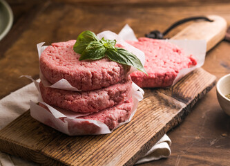 Raw burger patties on wooden background