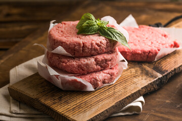 Raw burger patties on wooden background