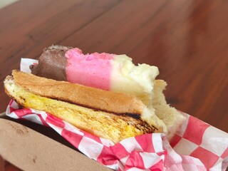 an ice cream sandwich with chocolate, strawberry, and vanilla flavors served in a soft bun with...