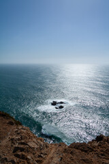 Vertical screen. Sun glittering on the surface of the Atlantic ocean with waves crashing against...