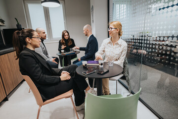 A group of colleagues seated around a table, enjoying coffee and engaging in conversation, fostering collaboration and teamwork in a contemporary workplace setting.