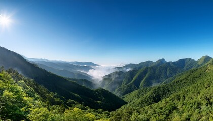 Obraz premium breathtaking panoramic view of misty green mountains under a clear blue sky capturing the serene beauty of nature and landscape