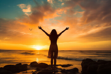 Silhouette of a woman at sunset over the ocean, arms raised above her head.