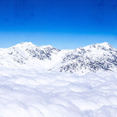 Fototapeta premium Snowy Mountain Range Floating Above a Sea of Fluffy White Clouds