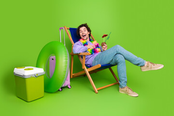 Young man enjoying leisure in a casual outfit with vacation props highlighted against green background for advertising