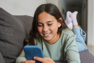 Young teenager girl using smartphone at home watching videos on social media - Domestic lifestyle, childhood and technology concept