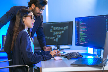 Senior engineer mentoring a junior female developer. Diverse tech team collaborating on a project,...
