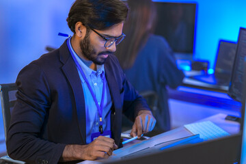 A UI/UX designer uses a stylus and tablet for digital prototyping. Focused professional working on...