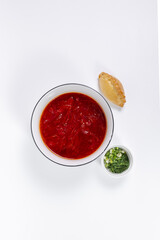 An appetizing portion of rich red borscht garnished with fresh herbs and spicy pies