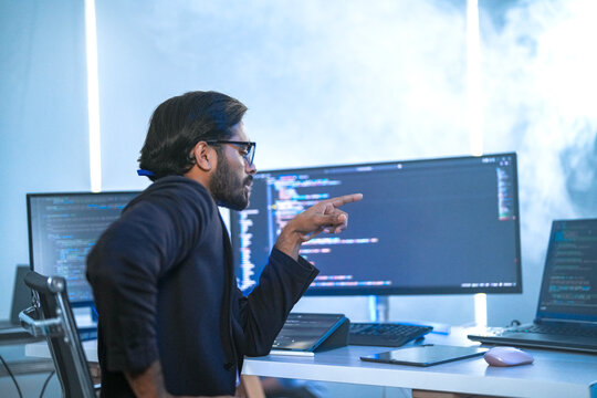 A back-end developer working on complex code in a futuristic command center. A lone programmer focused on a multi-monitor setup in a high-tech, atmospheric data hub.