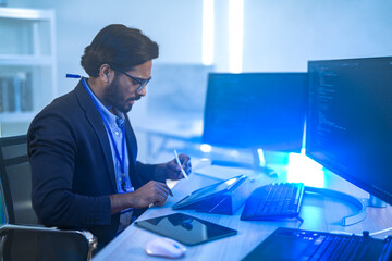 A back-end developer working on complex code in a futuristic command center. A lone programmer focused on a multi-monitor setup in a high-tech, atmospheric data hub.