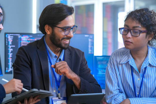 A team of software engineers celebrates a successful code deployment. They review the final user interface (UI) and user experience (UX) on a tablet after a collaborative debugging session.