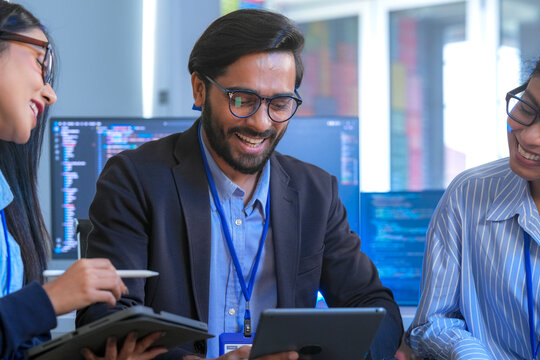 A team of software engineers celebrates a successful code deployment. They review the final user interface (UI) and user experience (UX) on a tablet after a collaborative debugging session.