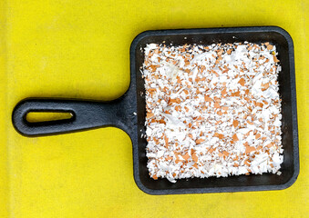 Crushed brown eggshells in pan on yellow background