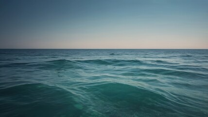 Fototapeta premium Tranquil Teal Ocean Waves Under a Pale Blue Sky at Dusk