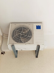 An old powerful air conditioner hangs on the balcony of a residential building
